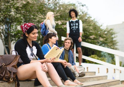 Student reading on steps of library