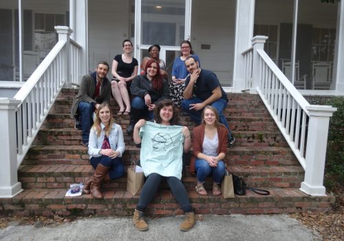 Eight Sigma Tau Delta students and Dr. Boyle seated on the front steps of Flannery O'Connor's house in Milledgeville, Georgia.